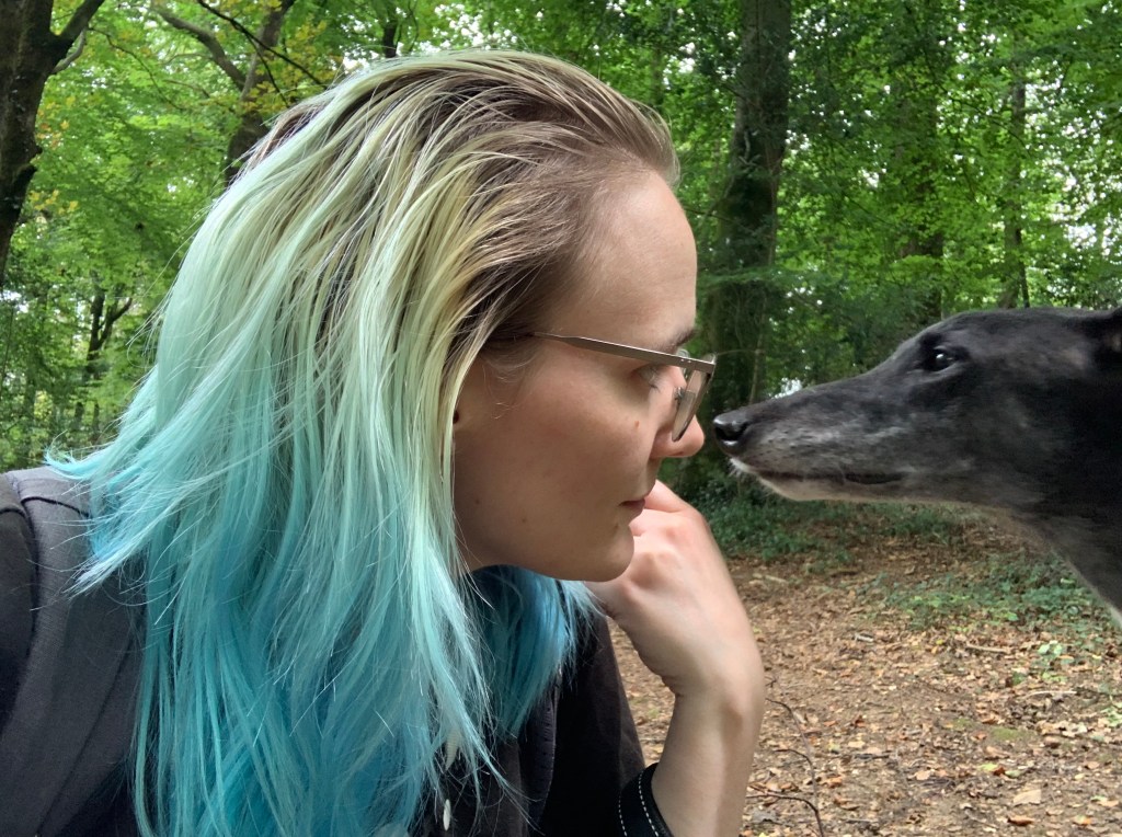 Non sharing a loving gaze with a black greyhound in a forest